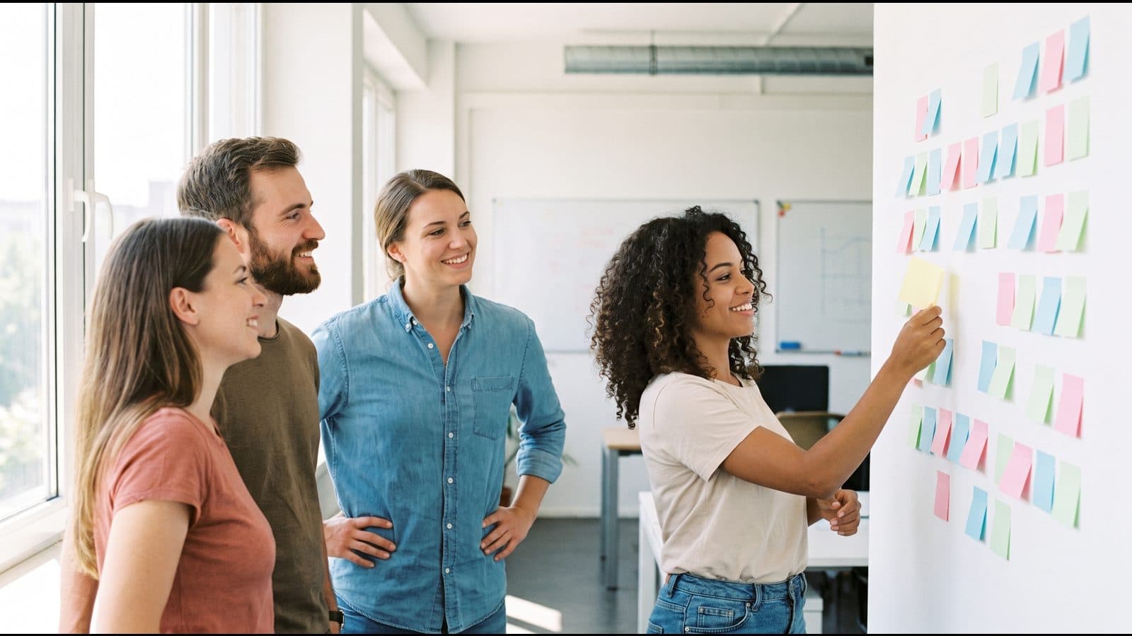 An agile team standing at a board of sticky notes, planning the next piece of work together.