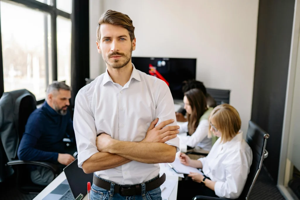 Confident project manager standing in front of a team, symbolizing leadership and the responsibility that comes with maintaining PMP certification.