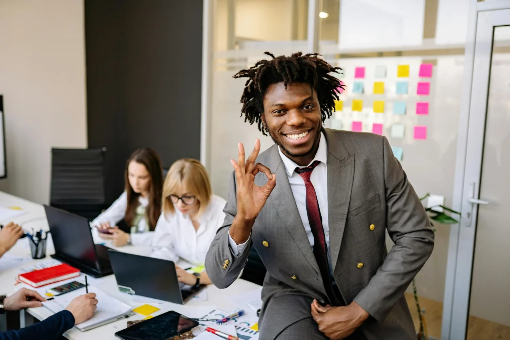 Confident young professional making an OK gesture in a modern office, symbolizing success after earning PMP certification in 2025