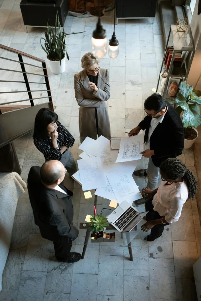 Group of professionals reviewing project plans and discussing strategies, symbolizing the efforts needed to pass the PMP exam with an above-target score.